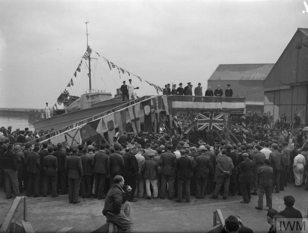 Hundreds of people gather around a boat about to be launched