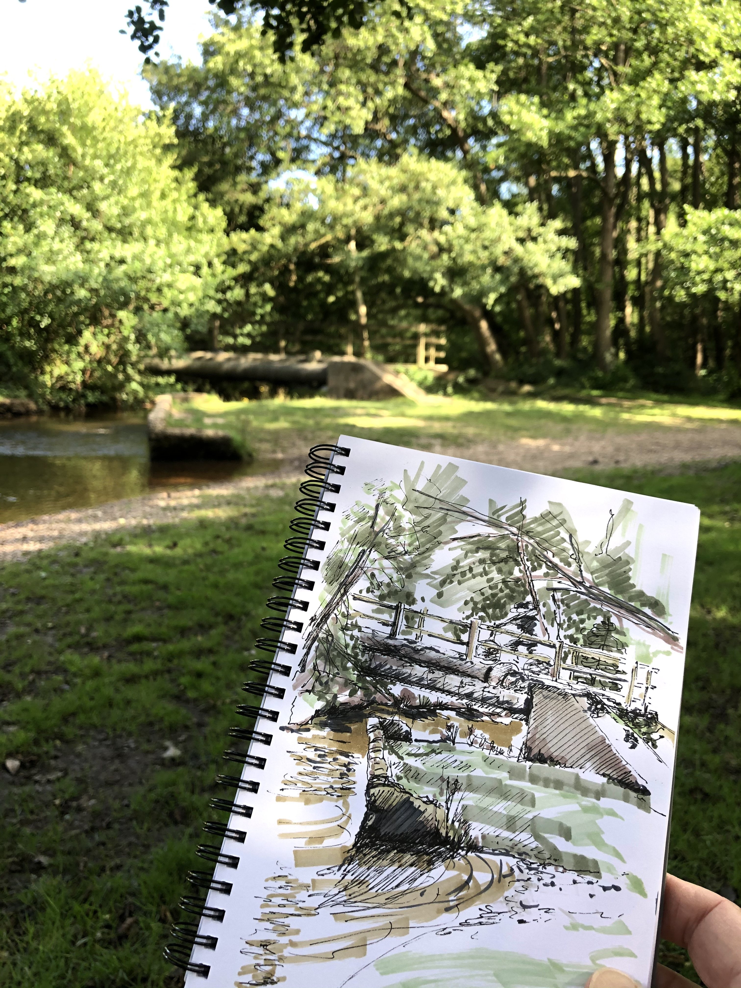 Trudi hollding a sketch by a pond