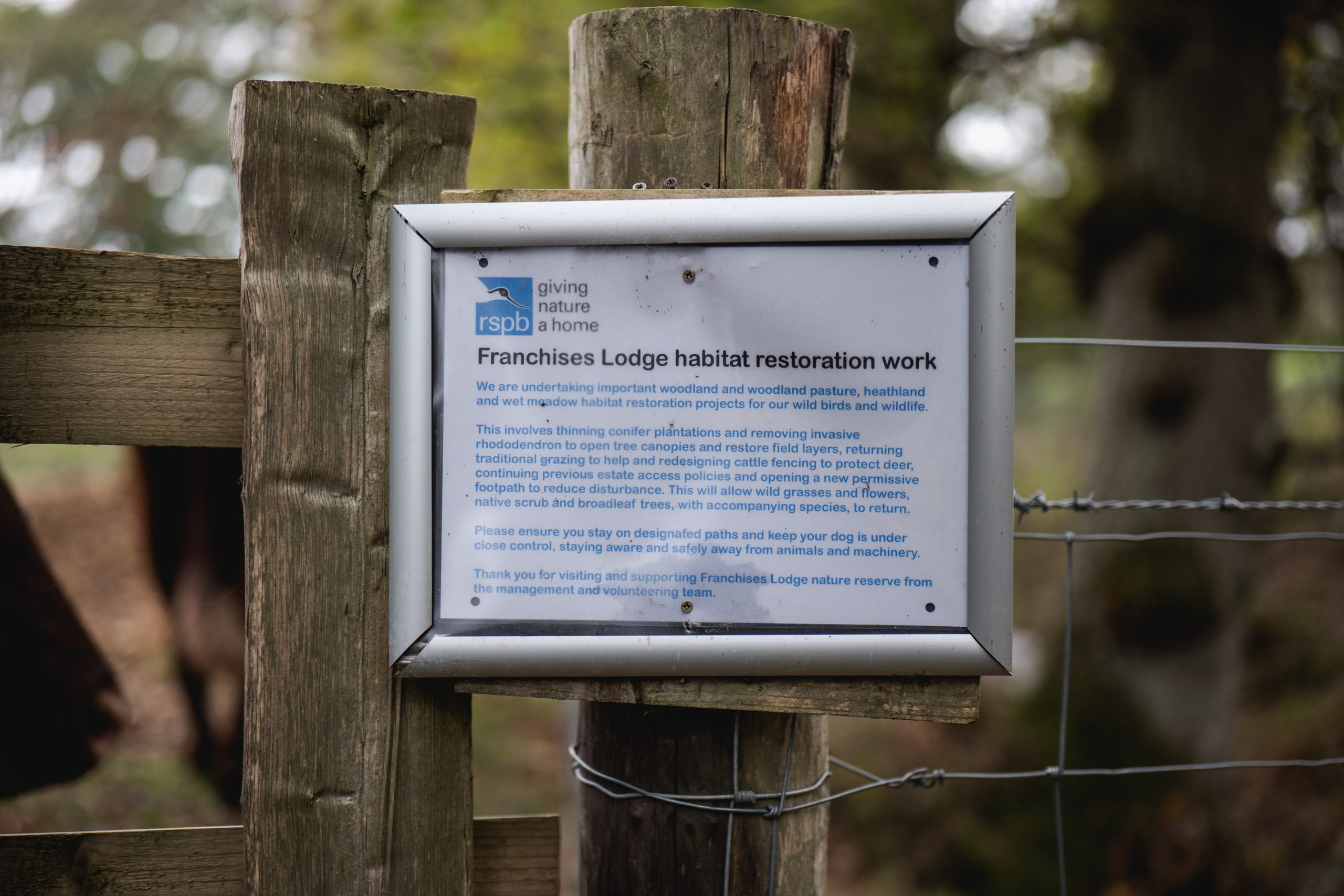 A sign hung on a gatepost reading that this is a habitat restoration area