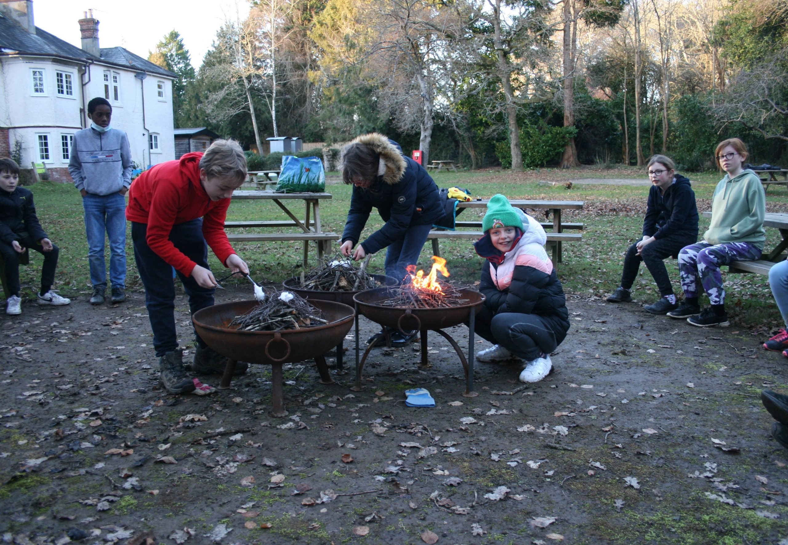 young people toasting marshmallows around fire