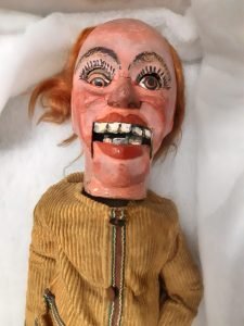An old ventriloquist doll with a broken eye, ginger hair and a yellow jumper