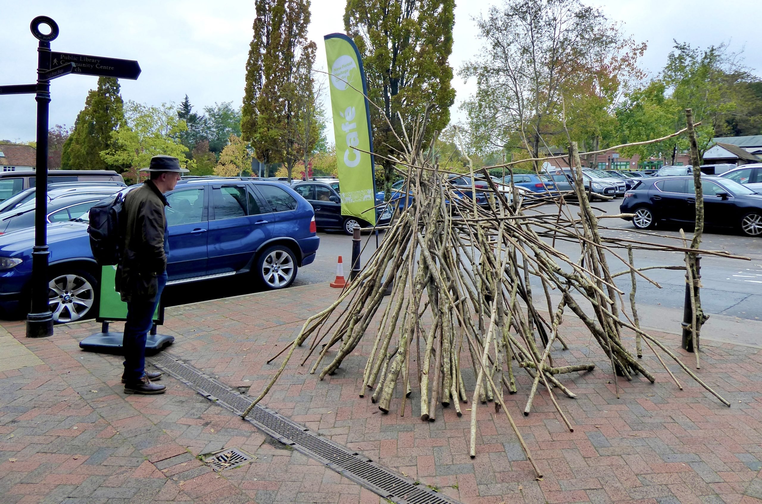 A den constructed outside of the New Forest Heritage Centre. A man in a hat is studying it.