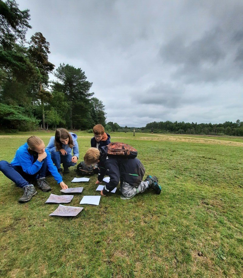 young people looking at worksheets on grass