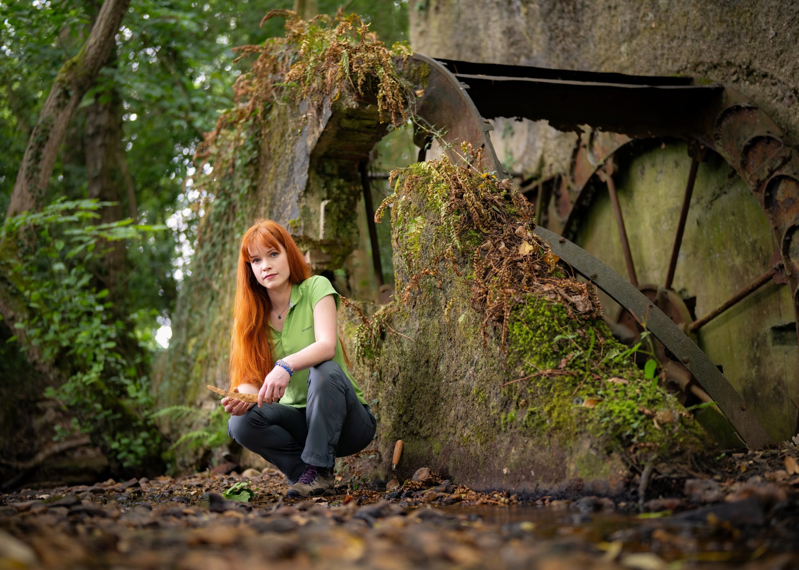New Forest NPA community archaeologist Hilde Van Der Heul crouching next to the remains of an old wheel and holding an artifact