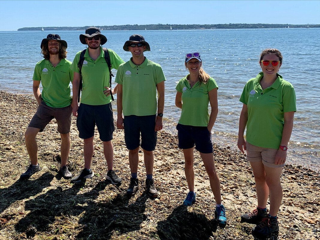 Former NPA apprentice and seasonal rangers including Ben Former NPA apprentice and seasonal rangers including Ben, all stood on a beach in NPA uniform on a sunny day