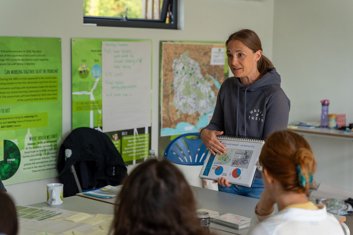 Gemma Stride (FHT) leads a session for the New Forest Youth Board on water quality Gemma Stride (FHT) leads a session for the New Forest Youth Board on water quality. She is stodd at the head of a table in a class setting holding some charts