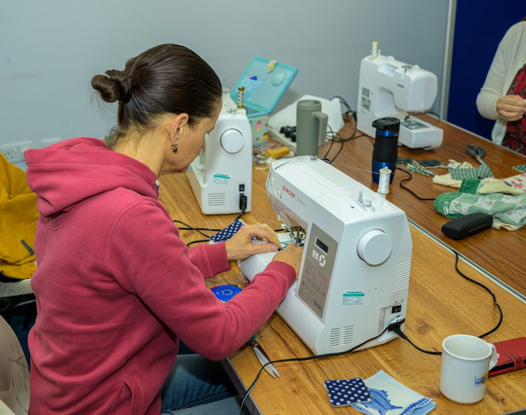 RACE Make Do and Mend A person using a sewing machine at a RACE Make do and Mend event