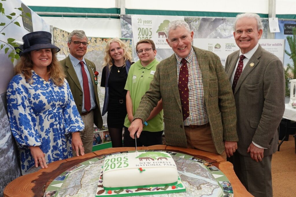 People standing in a tent around a table with a presentation cake