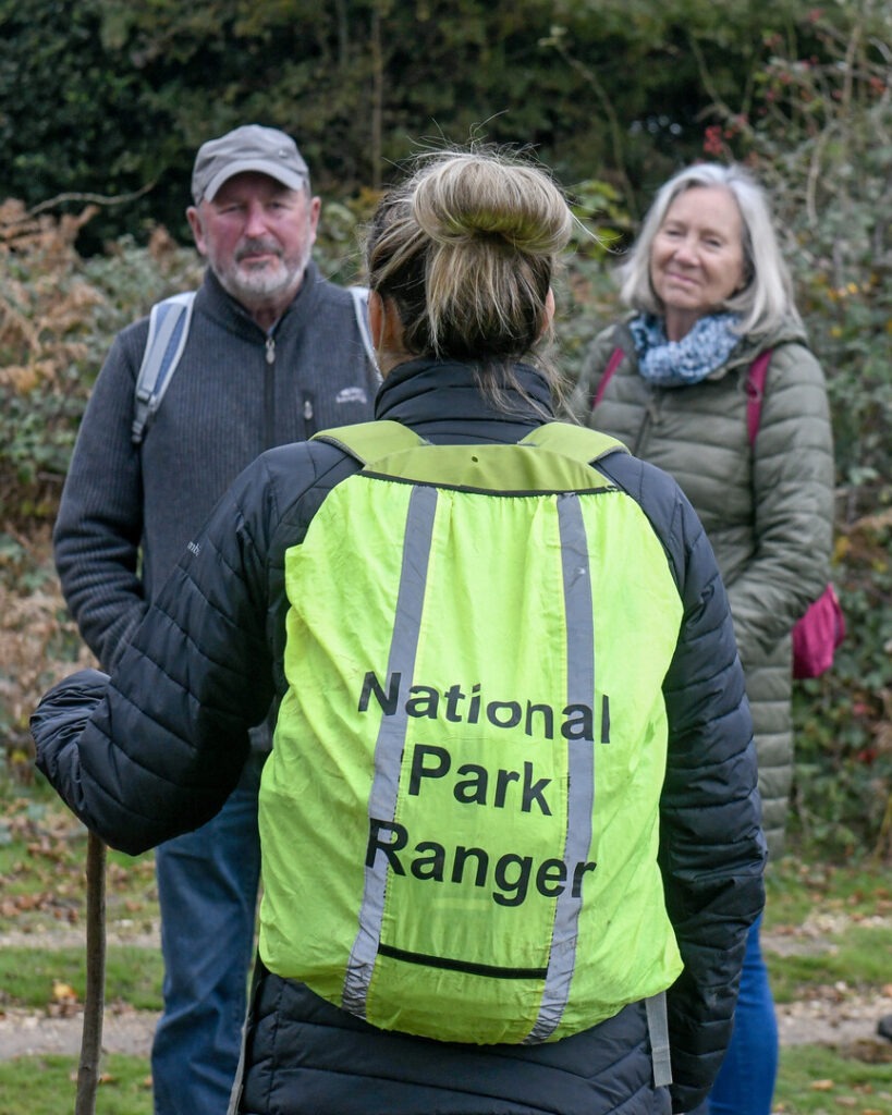 A ranger with a rucksack saying National Park Ranger speaking to two people