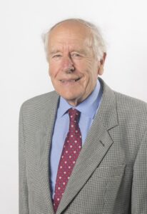 a man in a grey jacket blue shirt and red tie