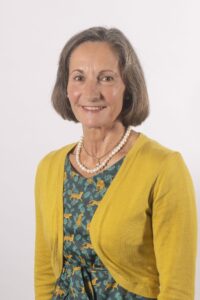A woman with a yellow cardigan, smiling