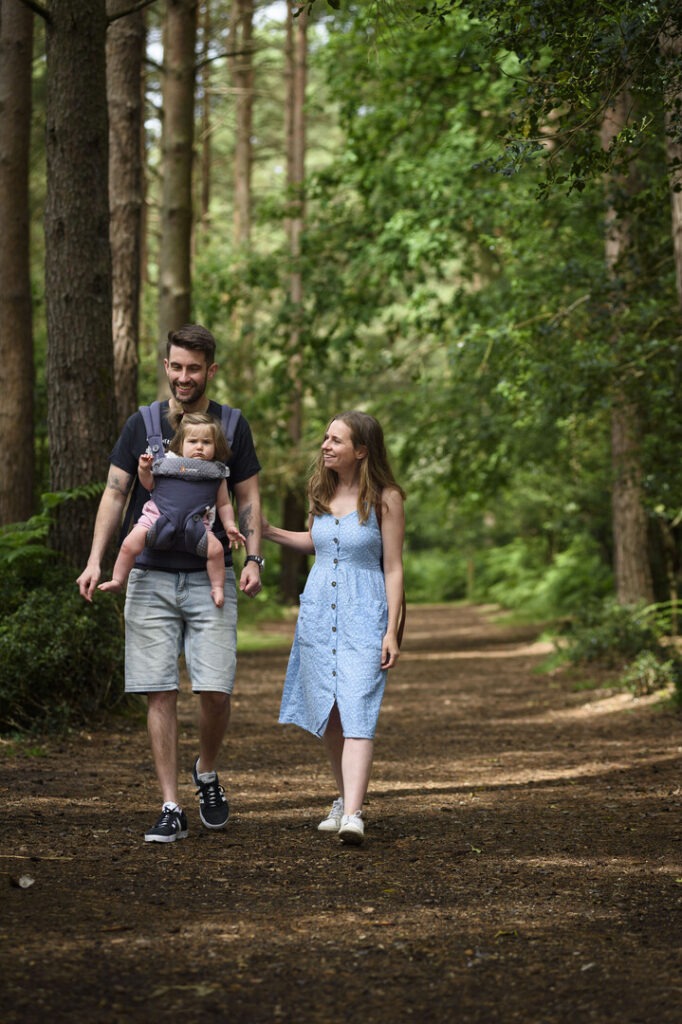 two people with a baby walking through woods