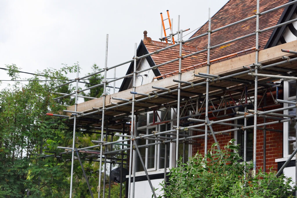 scaffolding and a ladder on a red brick building with white frontage