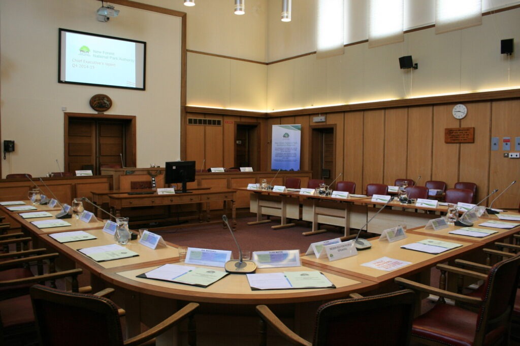 A wood panelled room with desks in a circle