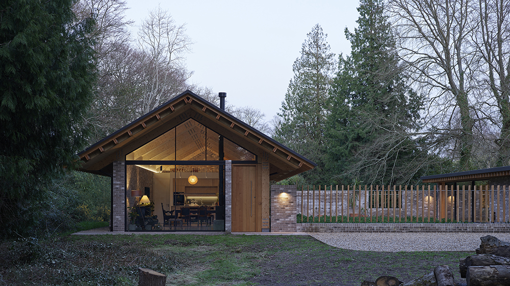The exterior of a house with lights on, at dusk.