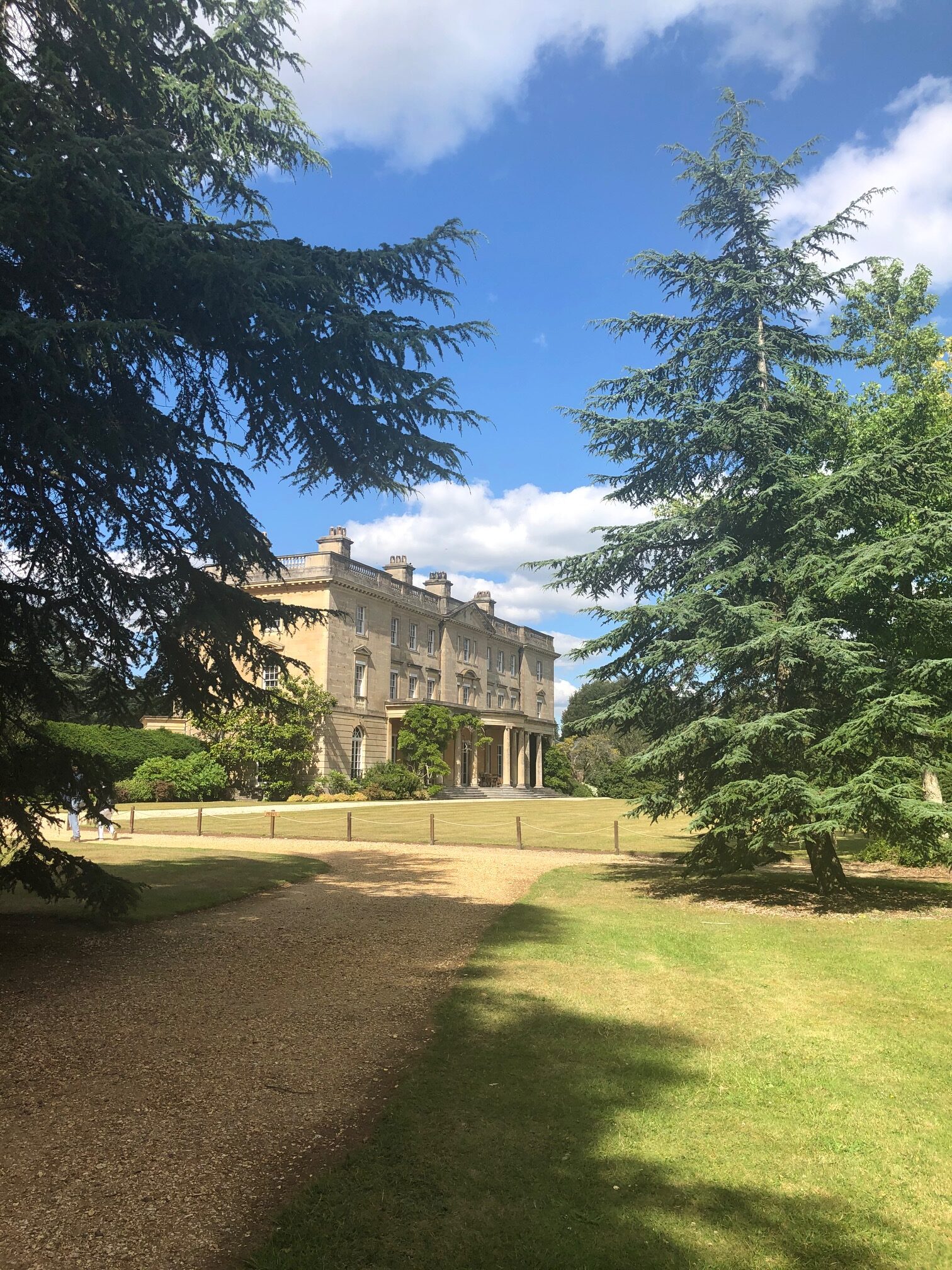 A stately home surrounded by trees with a drive running up to it