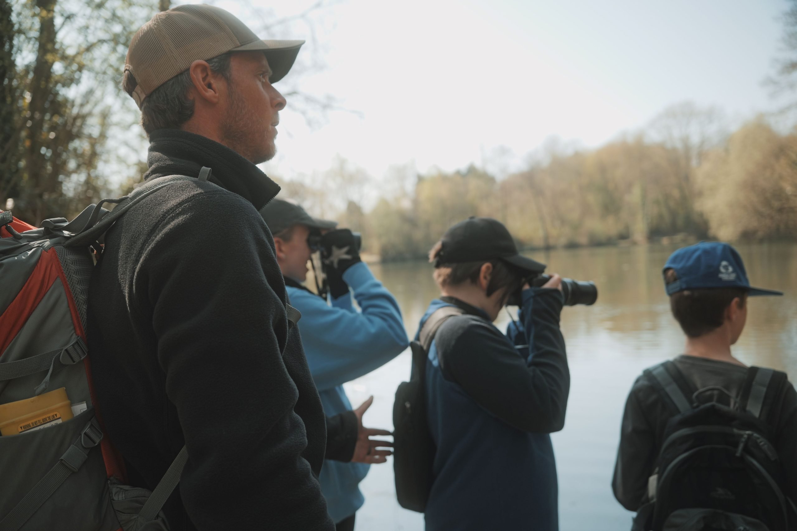 Young people with cameras looking out across the lake with an adult supervising