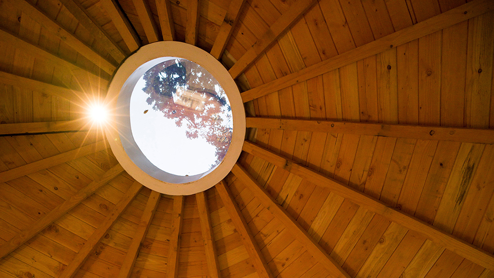 Looking upwards at a round skylight through a wooden roof