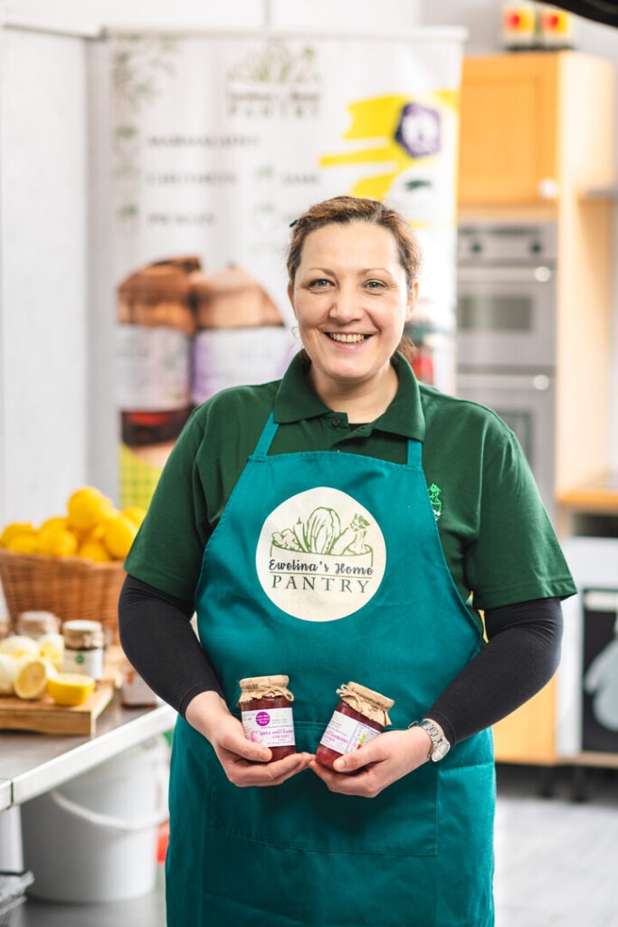 Lady in an apron holding two jam jars