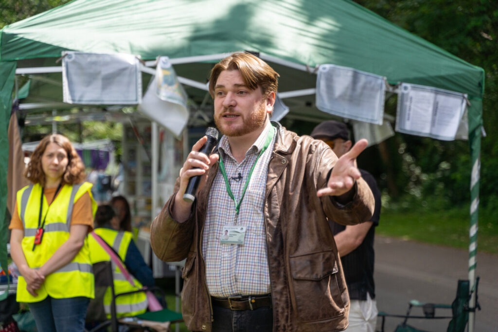A man with a microphone talking outdoors at an event