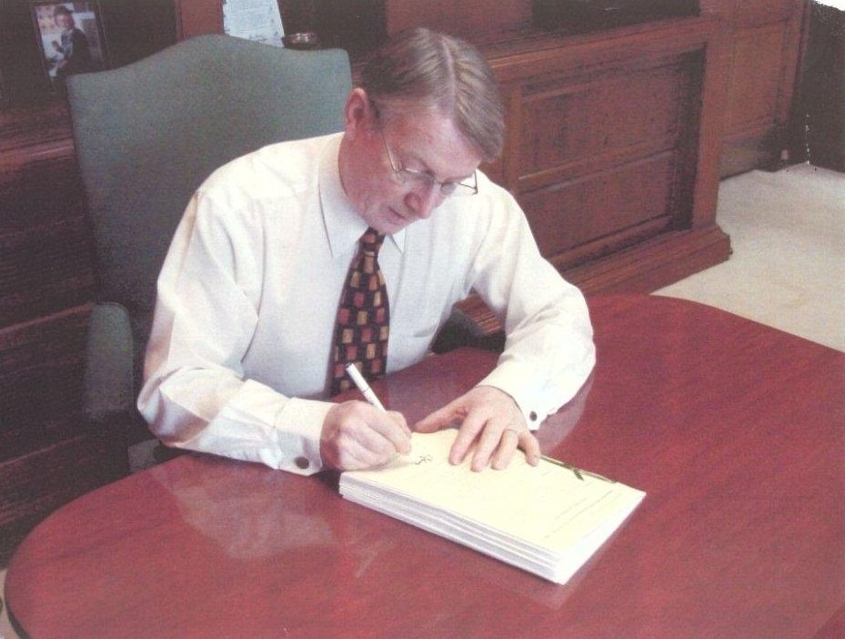 a person sitting at a desk writing on a piece of paper