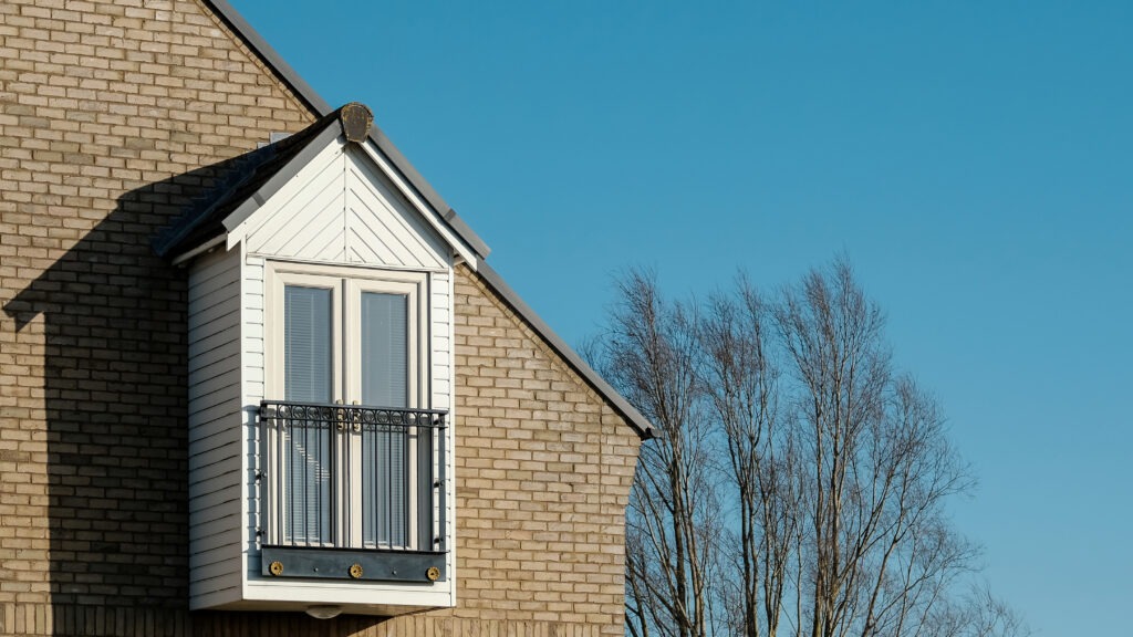 A small balcony on the side of a brick house extension
