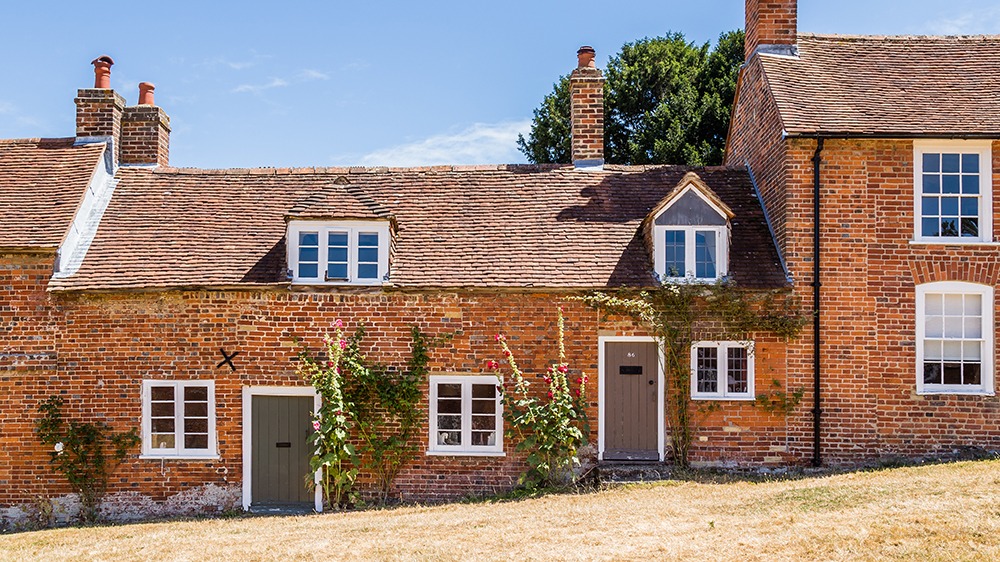 Row of old brick cottages with flowers growing up the walls