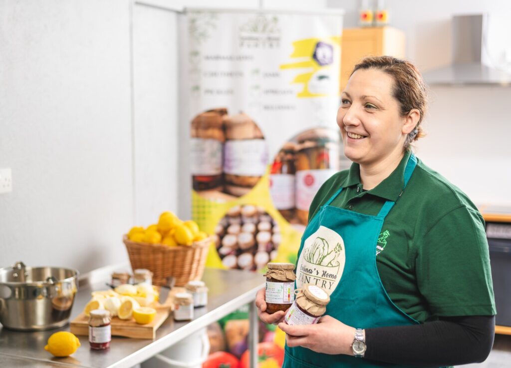 Lady in a kitchen holding jars of preserves