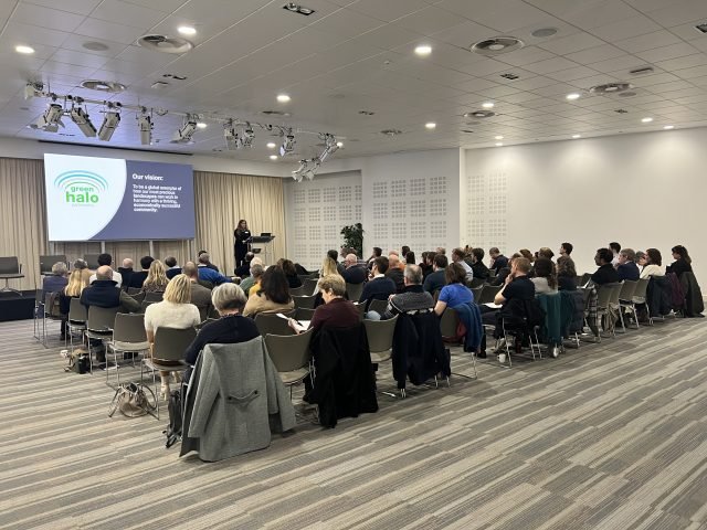 people sitting in a conference room looking at a speaker and presentation