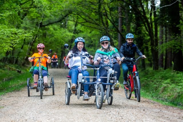 People cycling on different types of bikes in a forest