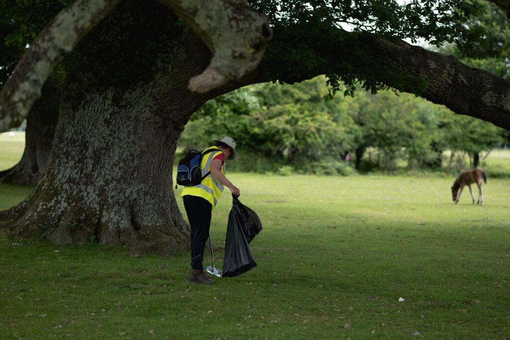 a person litter picking under a tree