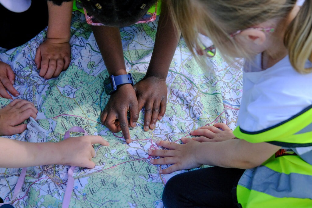 Four school children sat on a map of the New Forest and pointing at part of it