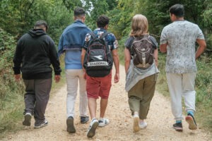 Four refugees and their support worker on a guided walk in the New Forest, all have their back to camera walking down a path