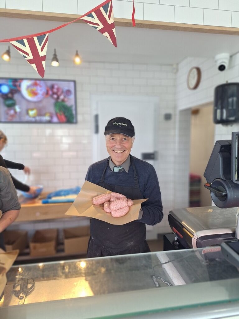 Man holding sausages behind a butchers counter