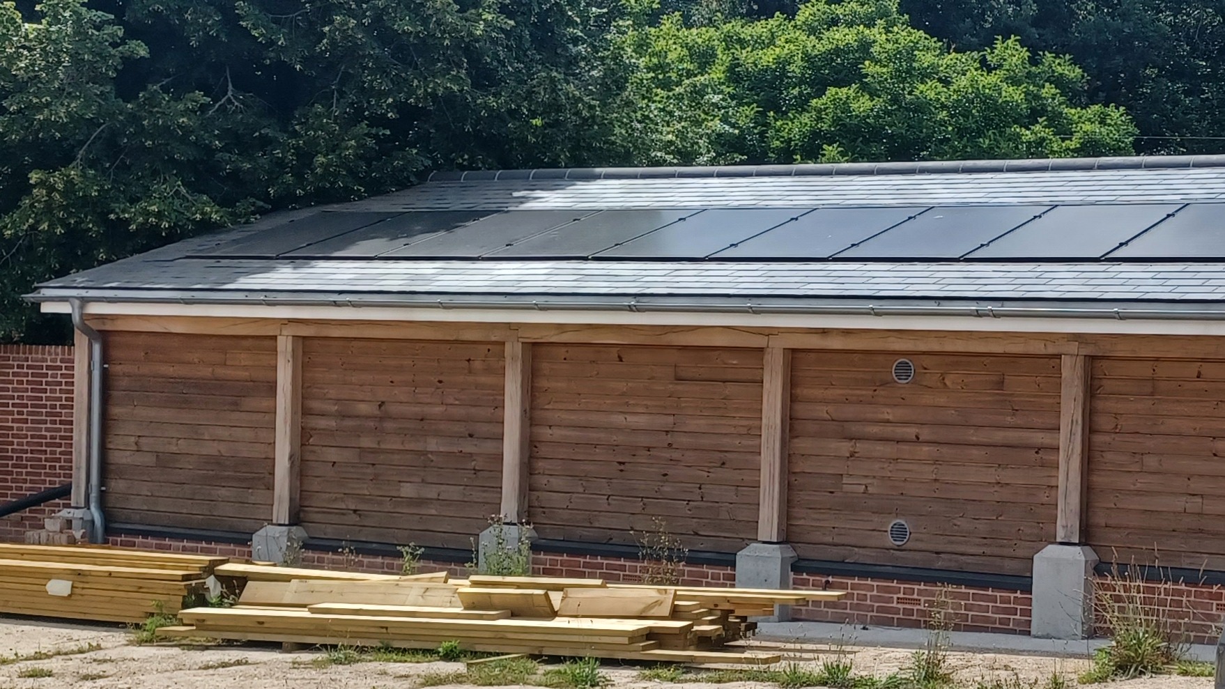 A long wooden-clad building with solar panels