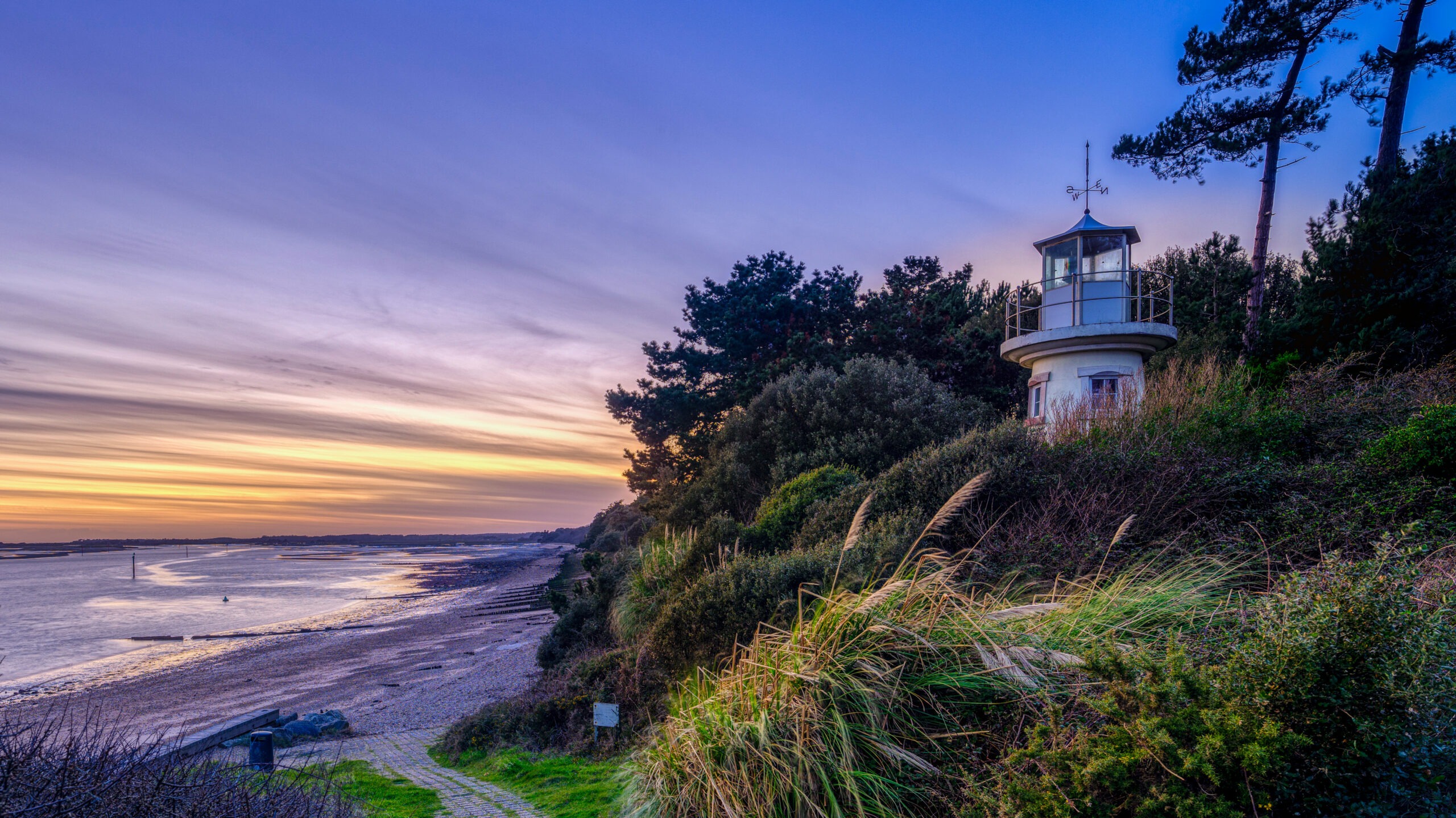 A lighthouse at sunset with the sea in the background