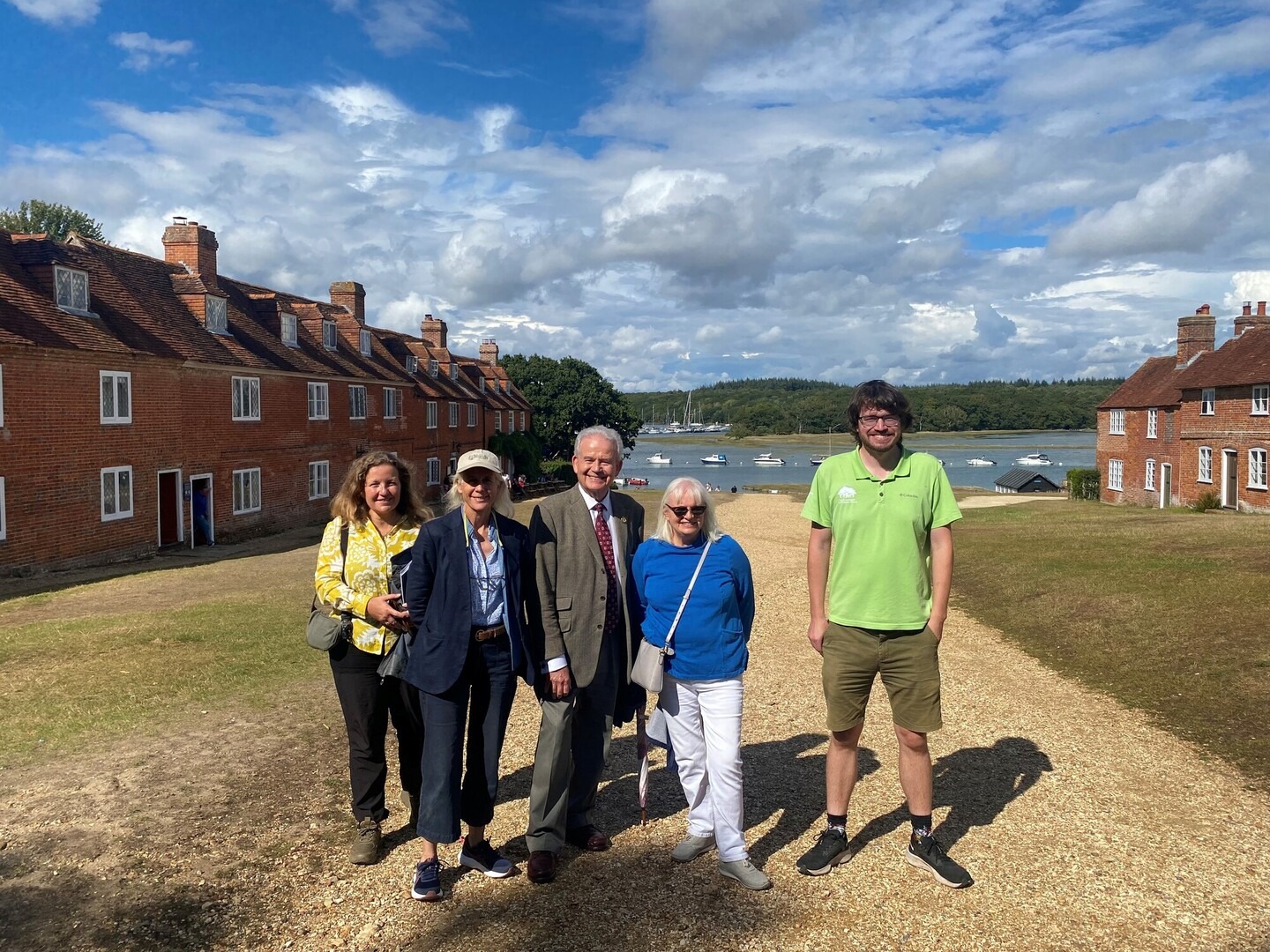 five people standing between rows of houses looking down to the sea behind them