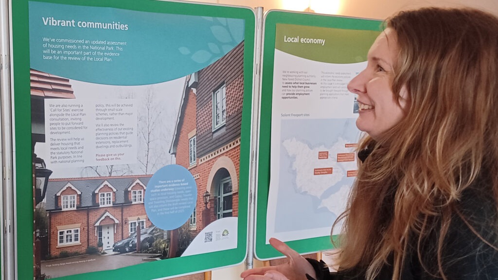 A woman talking to a member of the public in front of exhibition boards