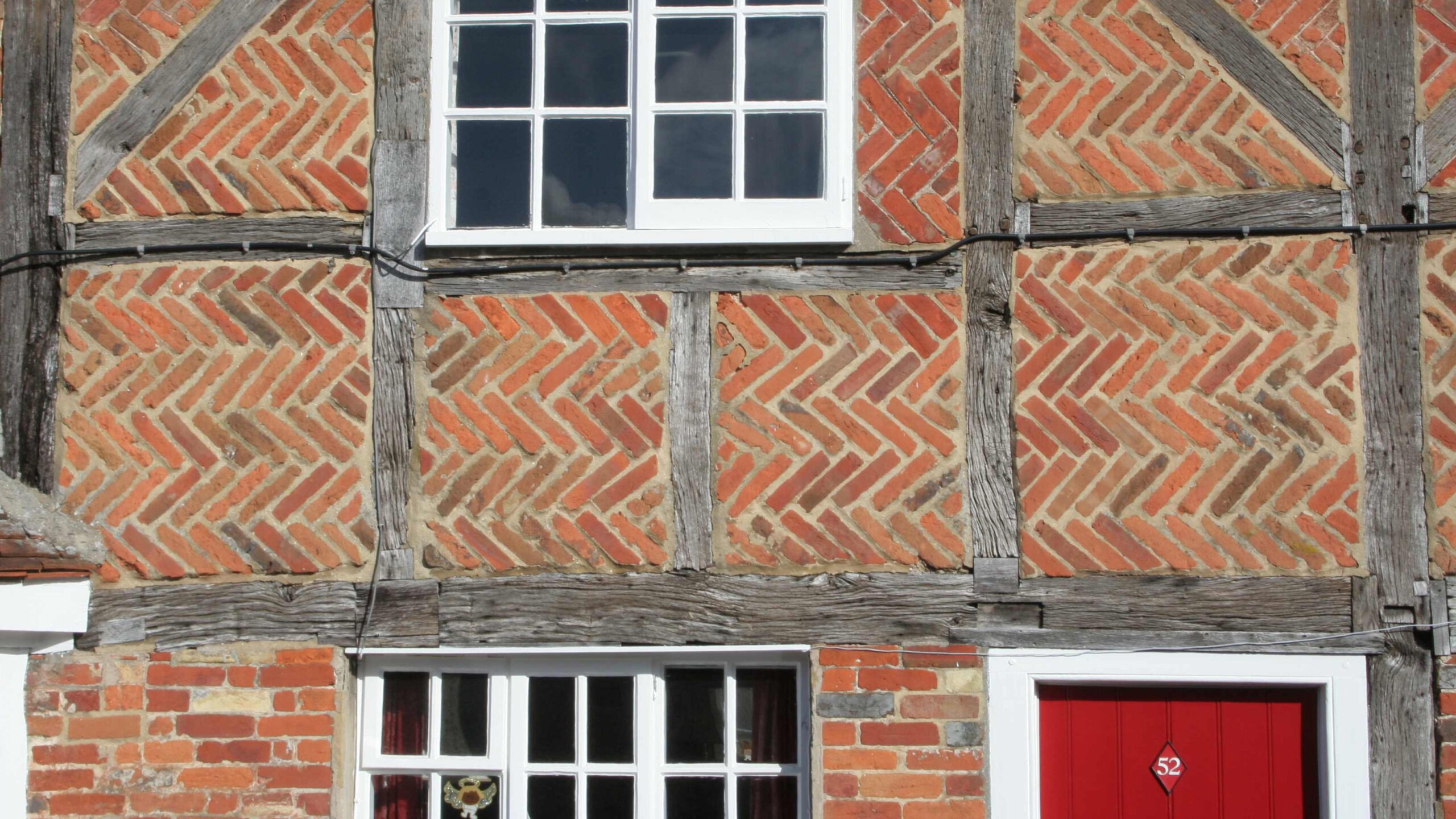 Close up of herringbone brickwork and windows on an old cottage