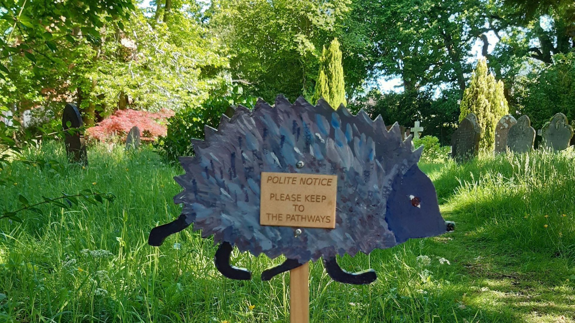 A hedgehog shaped sign asking people to keep to the path