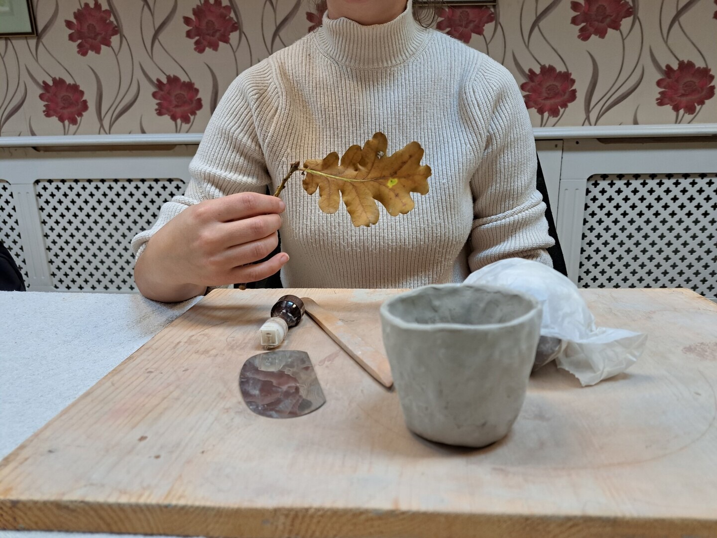 Person holding leaf with clay pot in the foreground