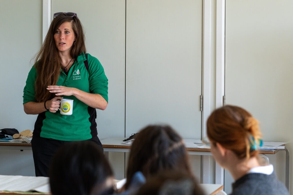 Forestry England staff member speaks to a group at a New Forest Youth Board meeting, holding a mug and gesturing