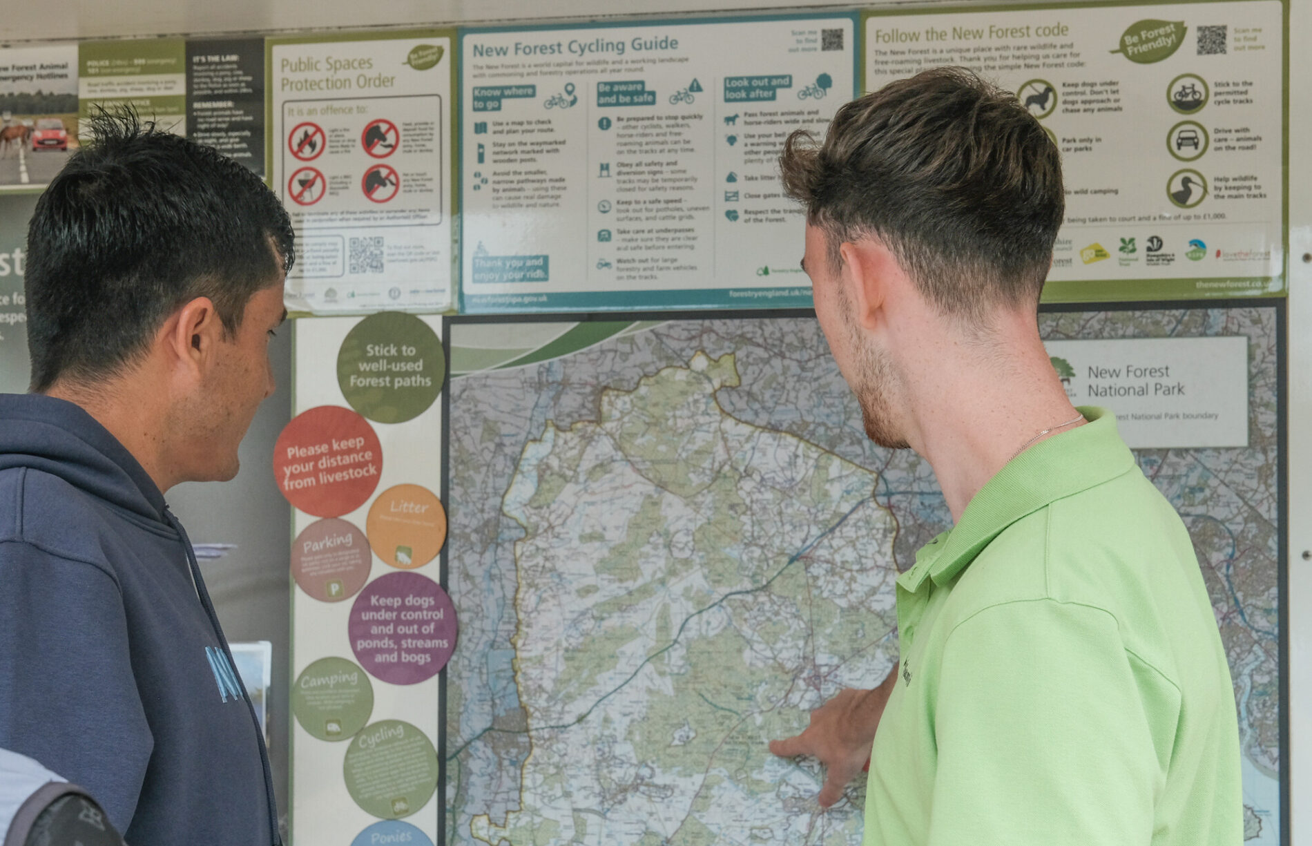Two men looking at an information stand about the New Forest, one is pointing at a map