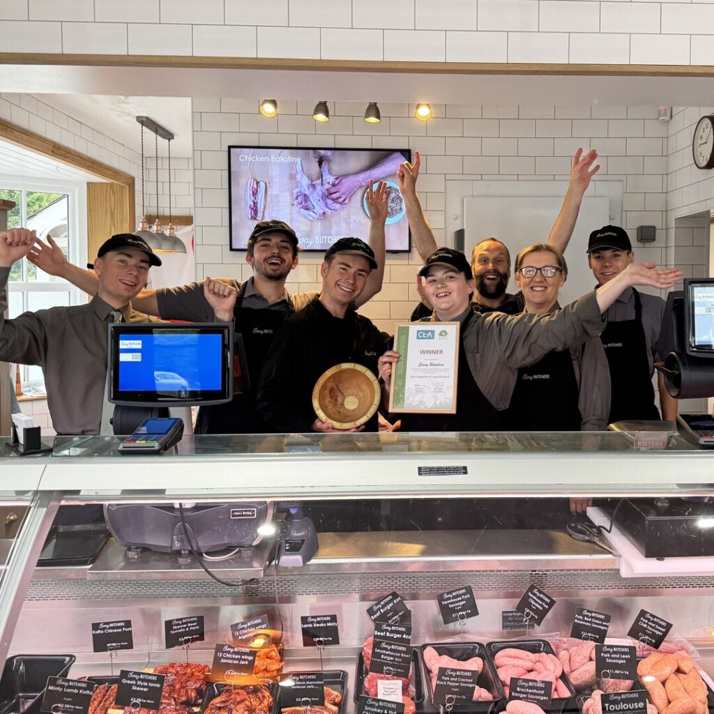 Group of people standing behind butchers counter with certificate