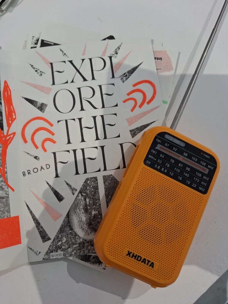 hand held radio on paper saying eplore the field