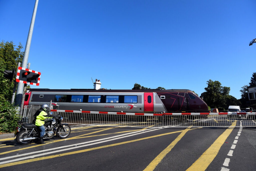 A cyclist waits at the railroad crossing at Brockenhurst station.