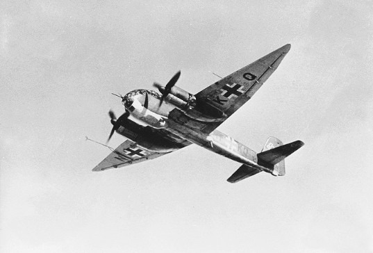 Black-and-white photo of a WWII German twin-engine aircraft in flight with Luftwaffe cross markings on the wings