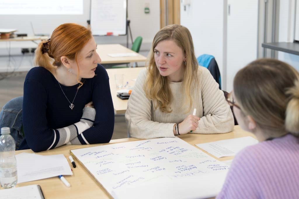 Three people sitting around a desk talking