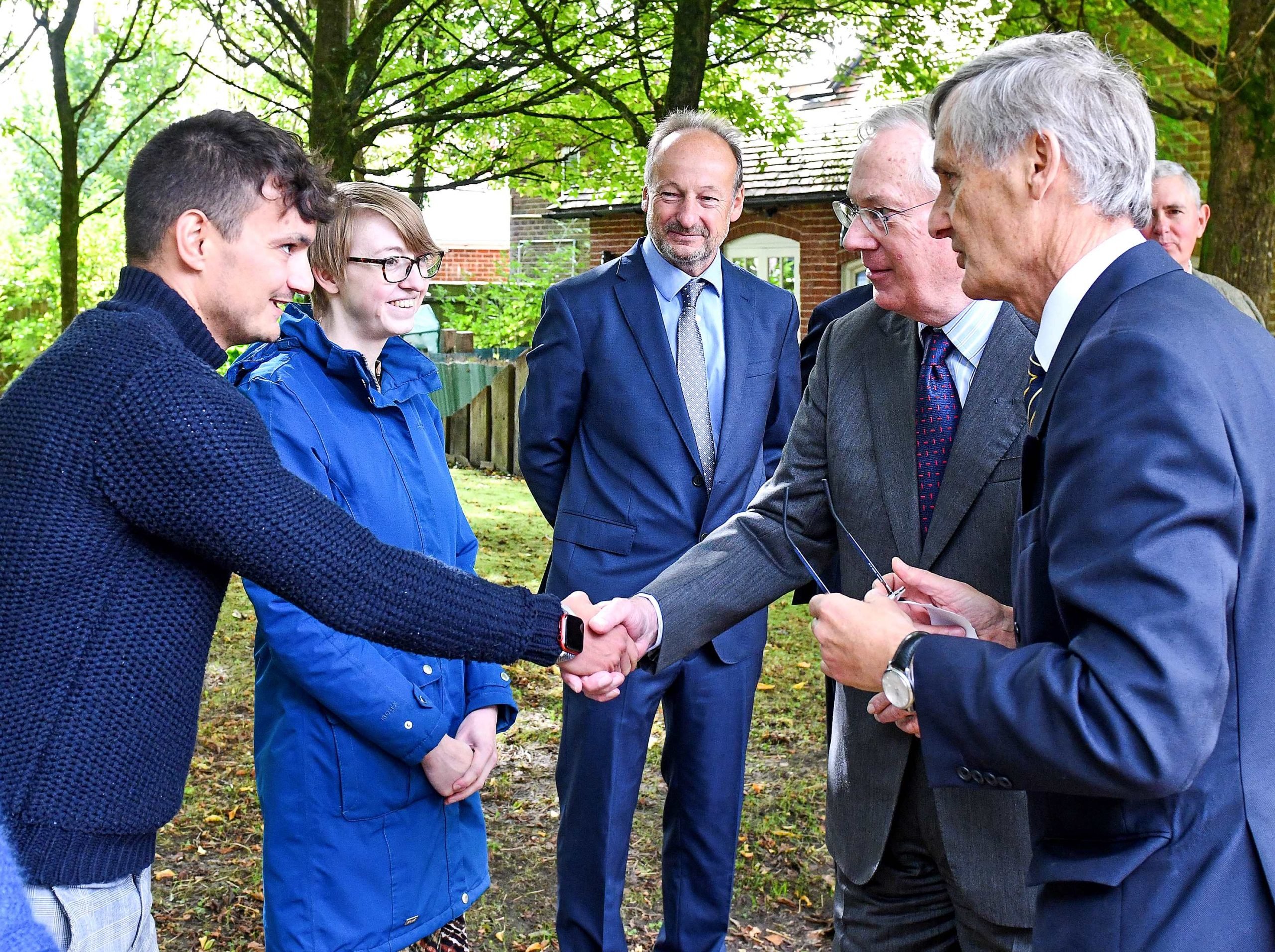 Duke shaking hands with people in a line with trees behind