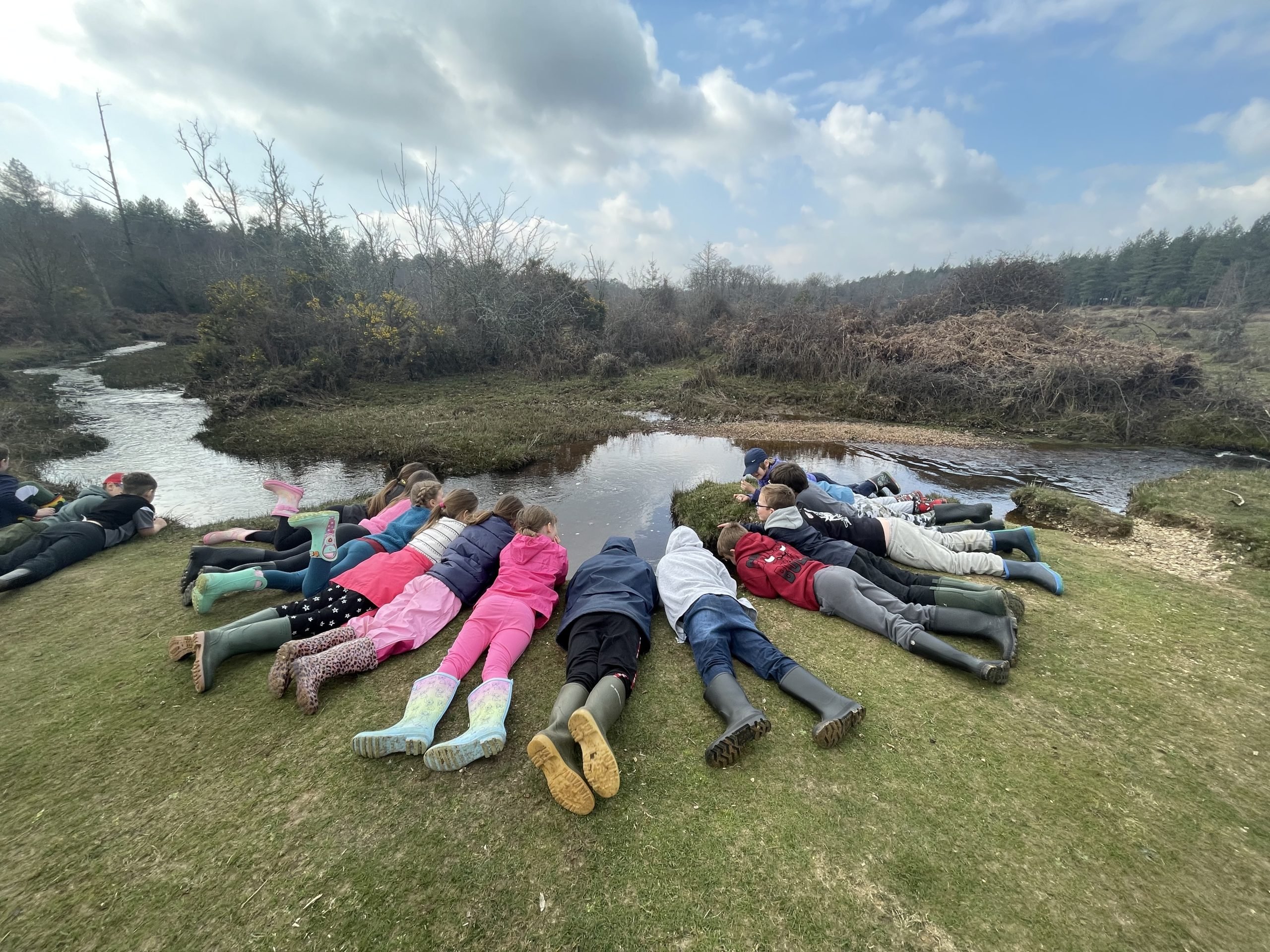 A group of school children lying by a river in the New Forest